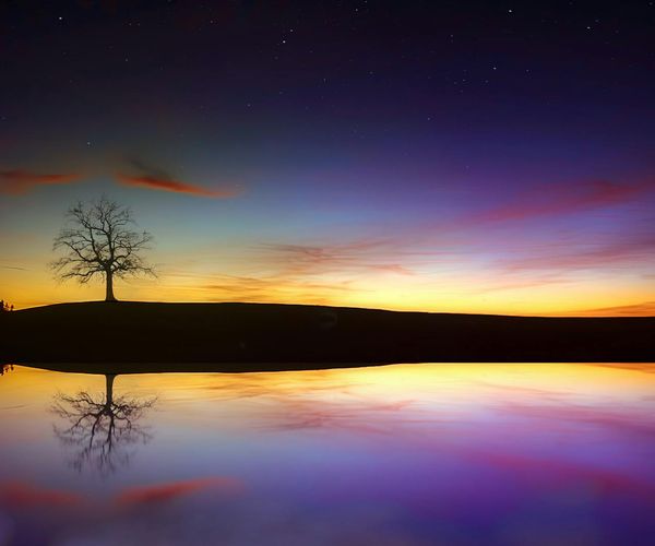 A serene scene of a sunrise over a calm lake.
